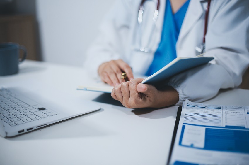 Middle aged female doctor working on laptop in doctor's room